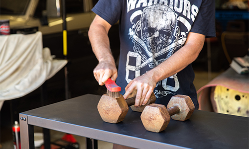 Man using wire brush to clean gym weights